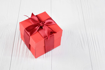 Red gift box with satin bow on wooden background