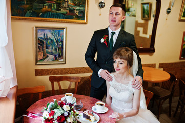 Fantastic wedding couple sitting and looking into each other's eyes in a small cozy cafe.