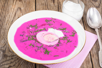 Rural dinner-beetroot soup with sour cream on wooden table