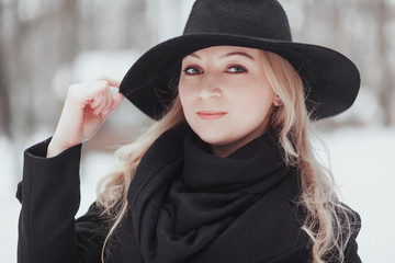 Woman winter snow nature portrait in black coat and hat