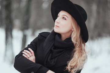 Woman winter snow nature portrait in black coat and hat