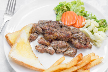 Grilled steak with french fries and vegetables and toast