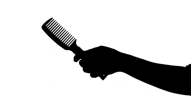 Female hand holding a rake comb Isolated black silhouette of a female hand holding a rake comb against white background