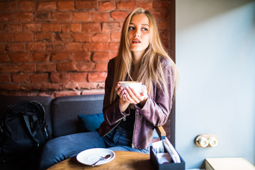Naklejka na ściany i meble Young beautiful woman in a cafe drinking coffee