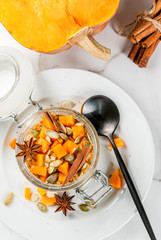 Healthy vegan food. Dietary breakfast or snack. Pumpkin pie overnight oats, with  pumpkin, yogurt, cinnamon, spices. In a glass, on a white marble table. Copy space top view