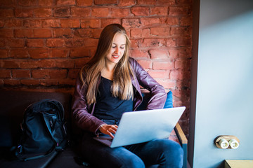 Portrait of a young beautiful businesswomen enjoying coffee during work on portable laptop computer, charming female student using net-book while sitting in cafe bar interior during morning breakfast