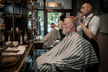 Senior man visiting hairstylist in barber shop.