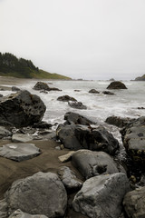 Fototapeta na wymiar black rocks along the shoreline on a foggy morning