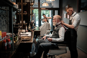 Senior man visiting hairstylist in barber shop. - Powered by Adobe