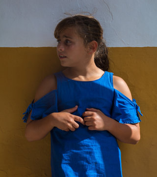 Ni&ntilde;a de 9 a&ntilde;os con vestido azul contra muro