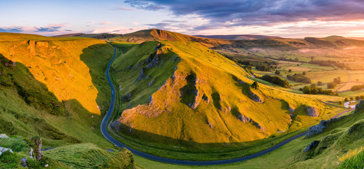 Aerial view of long winding road leading through mountains in the Peak District.