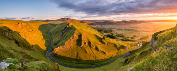 Wide panoramic view of Winnats Pass in the Peak District with vibrant morning light.