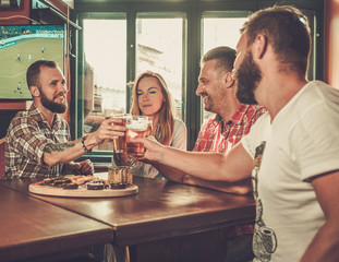 Friends drinking beer and watching soccer in a pub