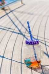 A transparent jar with a nice drink stands on the deck of the yacht during the rest.