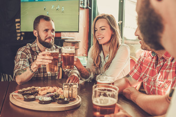 Friends drinking beer and watching soccer in a pub