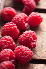 Raspberries closeup group in old brown rustic wooden box on morning light in studio