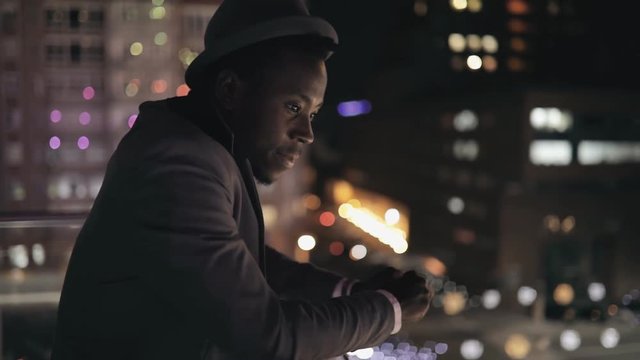 Young african businessman looking to night city from balkony