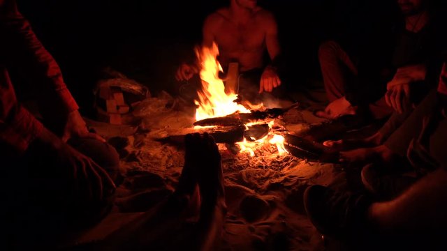 Group of Friends Sitting near bonefire at Night and Hanging Out. 4K UHD .
