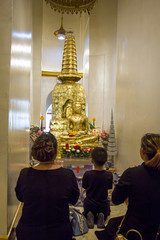 People praying to the golden buddha statue.