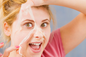 Woman peeling off gel mask from face