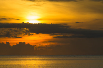 Fototapeta premium The sun shines through the clouds at dawn on the shore of the Gulf of Thailand.
