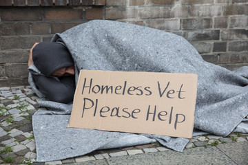 Male Homeless Sitting On A Street Asking For Help