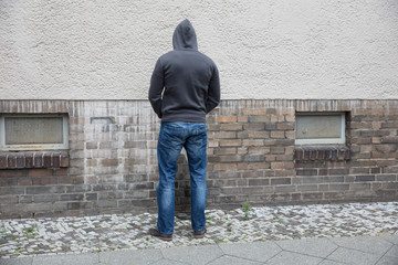 Man In Hood Peeing On Wall