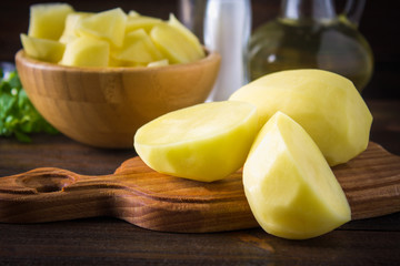 Raw peeled and sliced potatoes on an old weathered wooden table