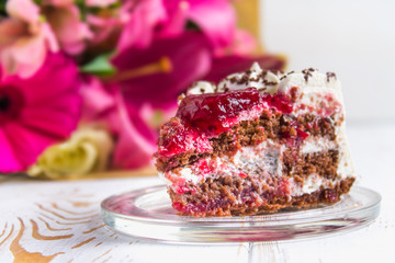 A piece of cake and a bouquet of flowers on a white wooden table. Celebrating the birthday, a gift.