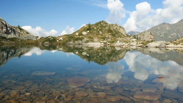 Mountains reflect on small alpine lake on the Bergamo Alps, northern Italy.