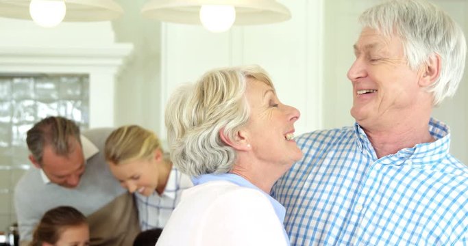 Smiling senior couple standing with arm around at home