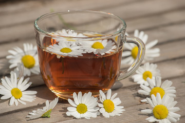 Herbal tea with chamomile on a wooden table on a summer sunny morning