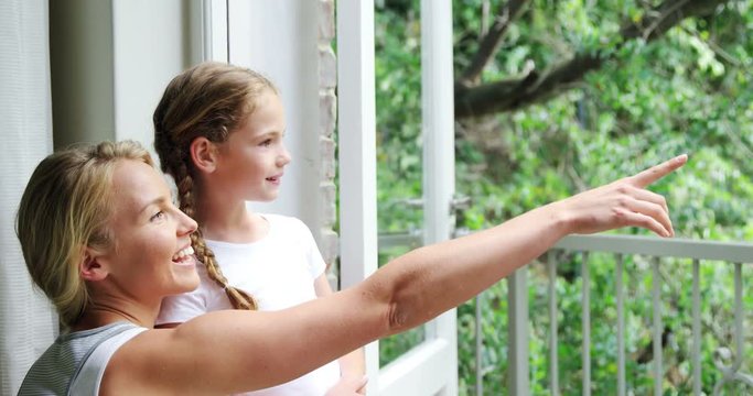 Mother and daughter standing together in balcony 