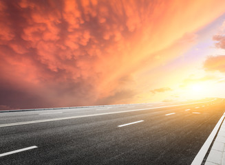 Fototapeta premium Asphalt road and beautiful sky landscape at sunset