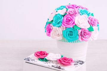 close-up of artificial flowers of roses from foam of  colors of blue, pink, white in a white pot and a wooden casket made with their own hands decorated with roses for decorating weddings, interiors