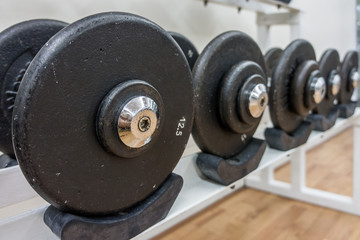 Many weight sizes of barbell plates in a gym. They are fitness equipments.