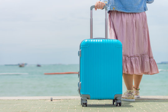 Modern blue travel baggage pulled by woman on beach. It is made from thermoplastic polymers .
