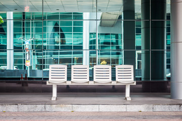 Seating at modern bus stop station. The white seats are made of metal.