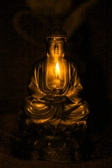 Bronze Buddha statue in darknes with candle