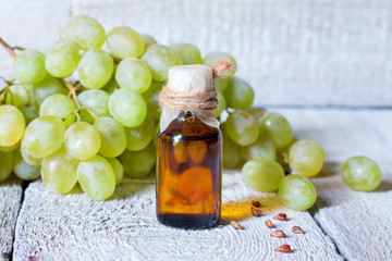 Bottle with grape seed essential oil on a wooden table