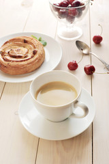coffee in a mug, cupcake with cinnamon cherries on white