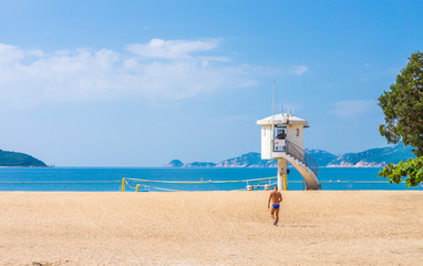 Tourist and enclosed lifeguard patrol tower on beach. They are at Repulse Bay in Hong Kong.