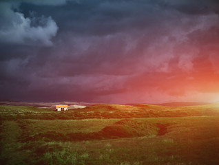 Naklejka na ściany i meble Travel to Iceland. The charming rustic rural house on dark cloudy sky background