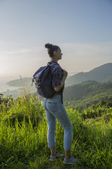 Hipster young girl with backpack enjoying sunset on peak of foggy mountain. Tourist traveler on background view mockup.