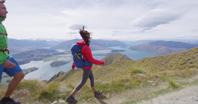 Hiking couple tramping up famous hike to Roys Peak on South Island, New Zealand. Hikers enjoying outdoor active lifestyle in beautiful nature on famous tourist destination, New Zealand.
