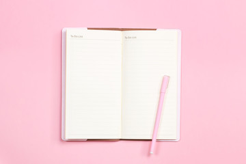 Pink notebook and pen to take notes on top of pink pastel desk.