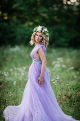 Fototapeta premium beauty woman portrait with wreath of flowers on head. bride in purple dress Outdoor. soft focus