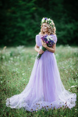 beauty woman portrait with wreath of flowers on head. bride in purple dress with bouquet of wildflowers .Outdoor. soft focus