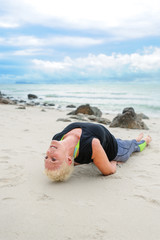 Beautiful mature aged woman doing yoga on a desert tropical beach