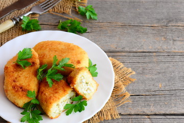Stuffed vegetable cutlets on a serving plate and on a vintage wooden background with copy space for text. Cauliflower potato cutlets stuffed with boiled sliced eggs. Rustic style. Closeup